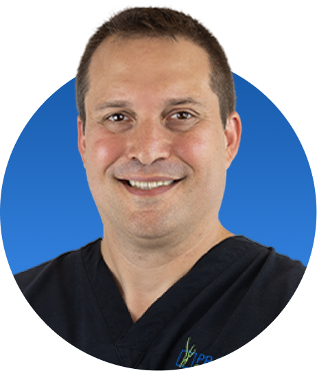 Chiropractor in black scrubs smiling against blue background