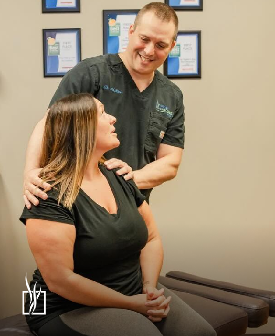 Chiropractor consulting with female patient, both smiling in clinical setting