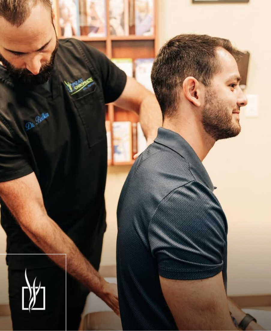 Chiropractor performing spinal examination on male patient in treatment room