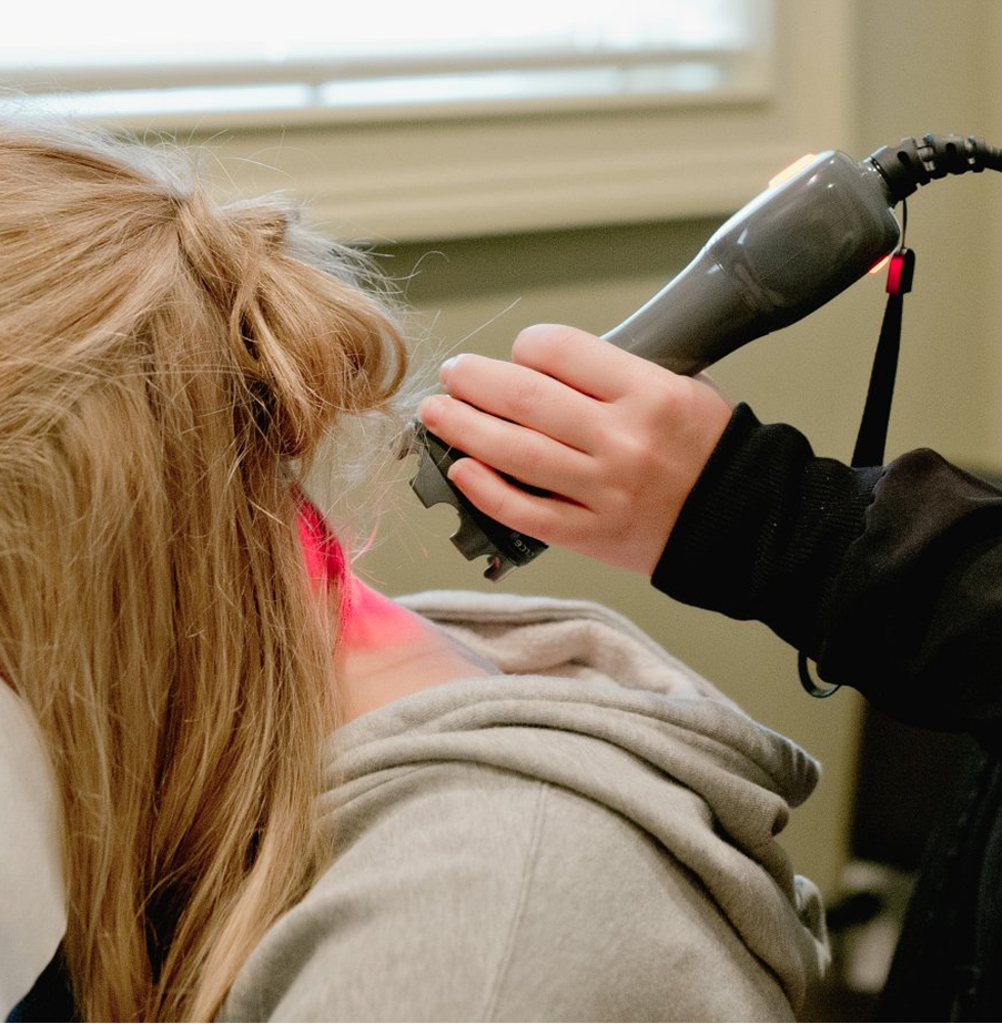 Therapeutic laser treatment applied to patient's neck and shoulder area