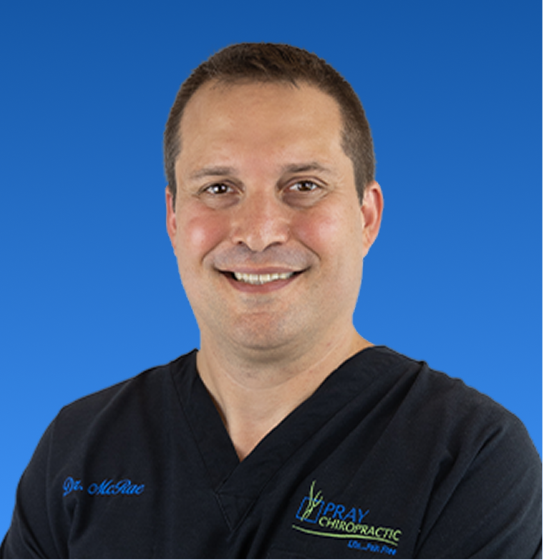 Jason McRae, D.C., chiropractor wearing black scrubs with practice logo
