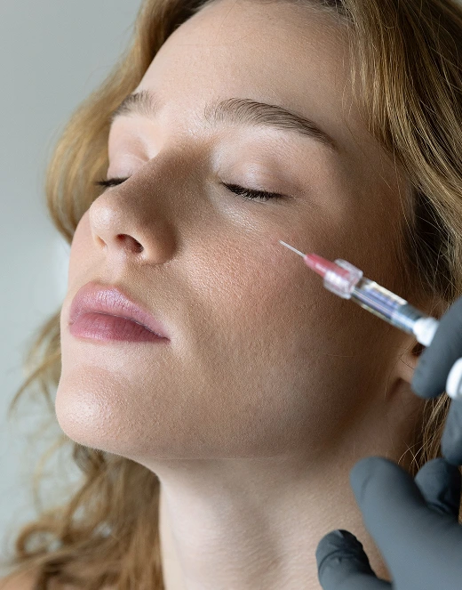 Practitioner injecting filler into woman's cheek with syringe