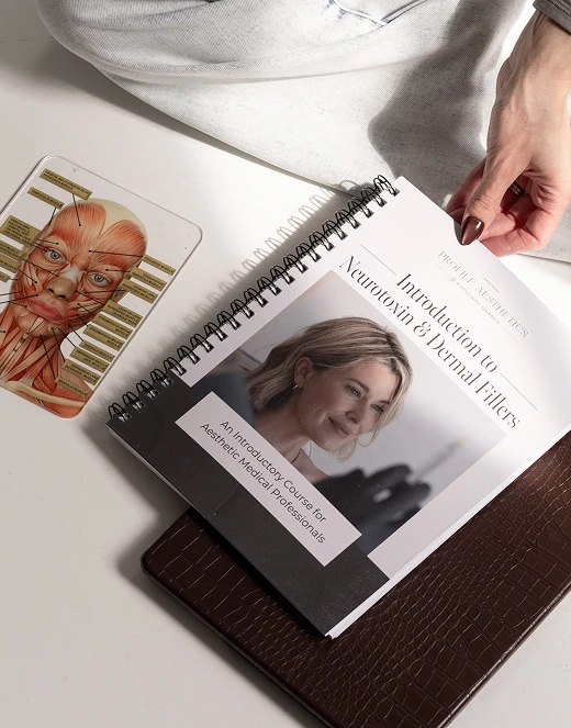 Hands holding open treatment guide showing facial anatomy chart and patient photo