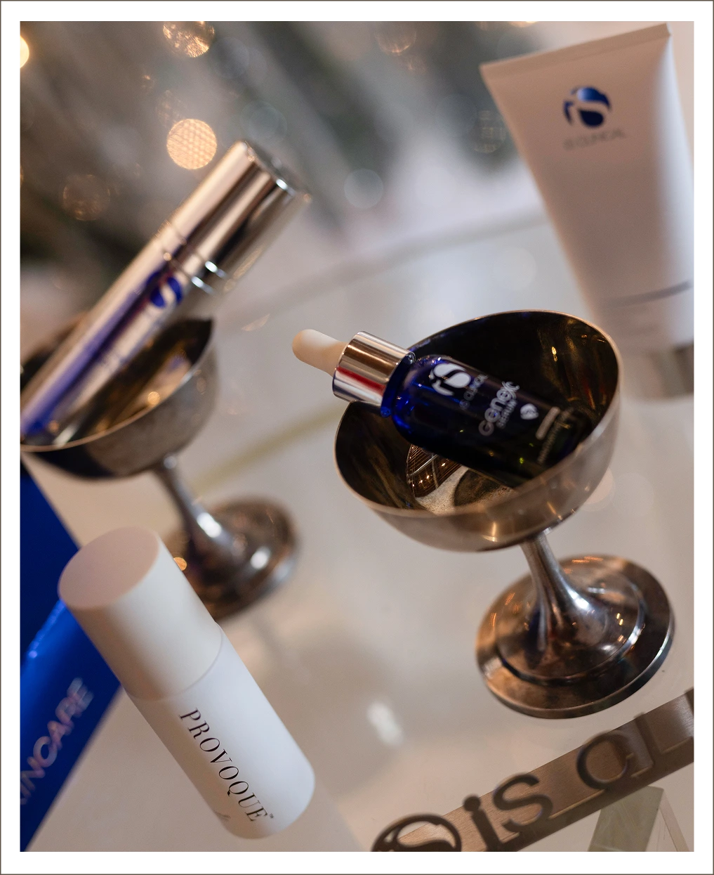 Skincare product bottles and serums with blue branding displayed on reflective surfaces