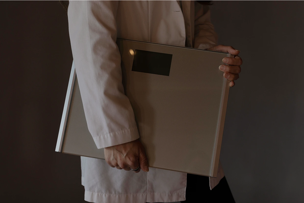 Person in white coat holding digital scale for body weight measurement