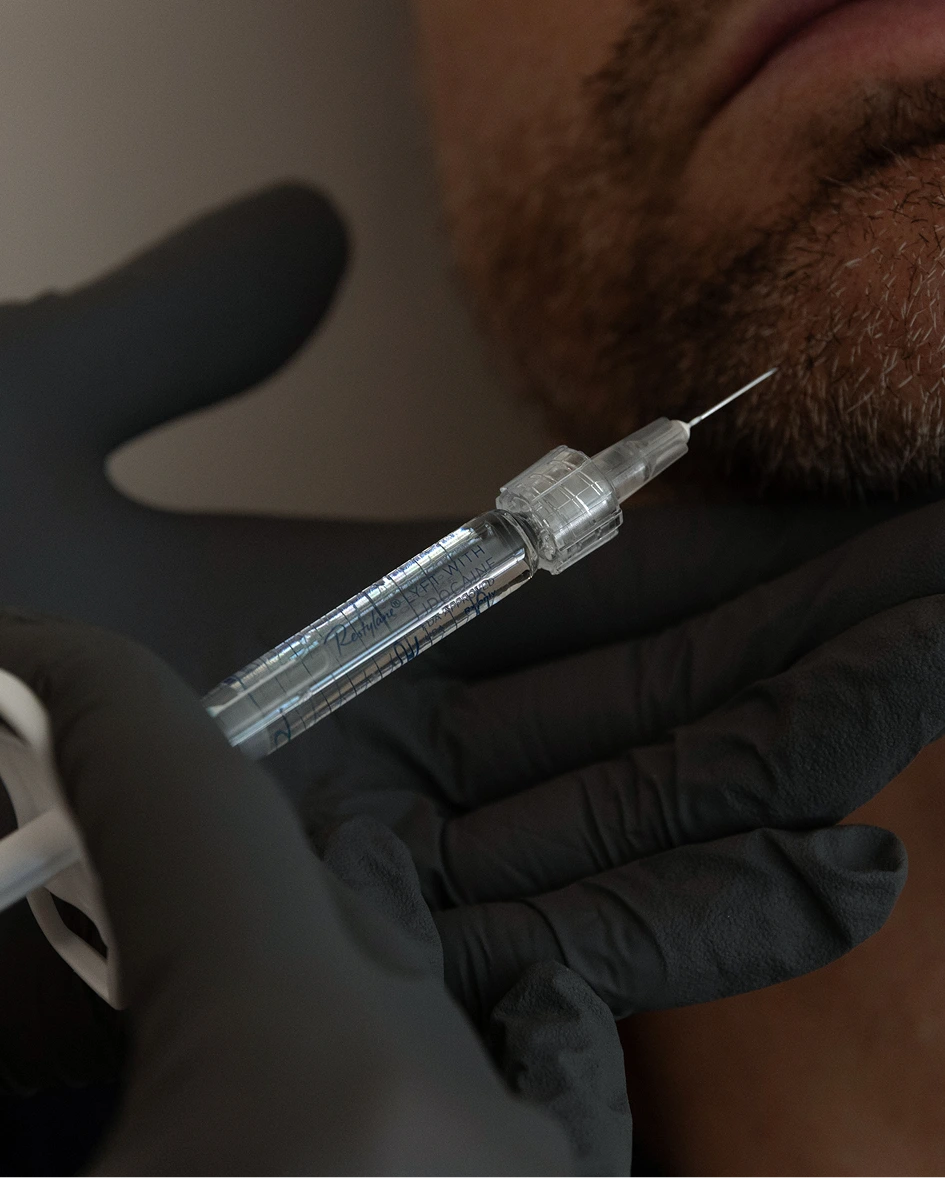 Gloved hands holding injectable syringe near person's face
