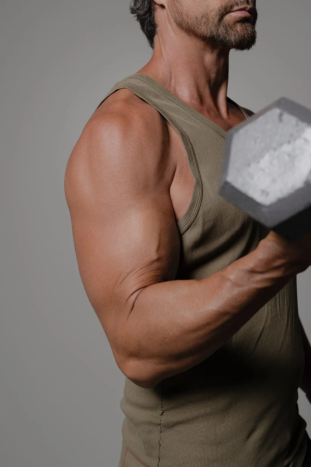 Man holding a dumbbell, displaying muscular arm and shoulder definition