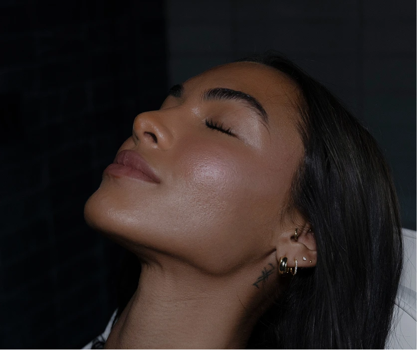 Woman's face in profile with smooth, radiant complexion against dark background