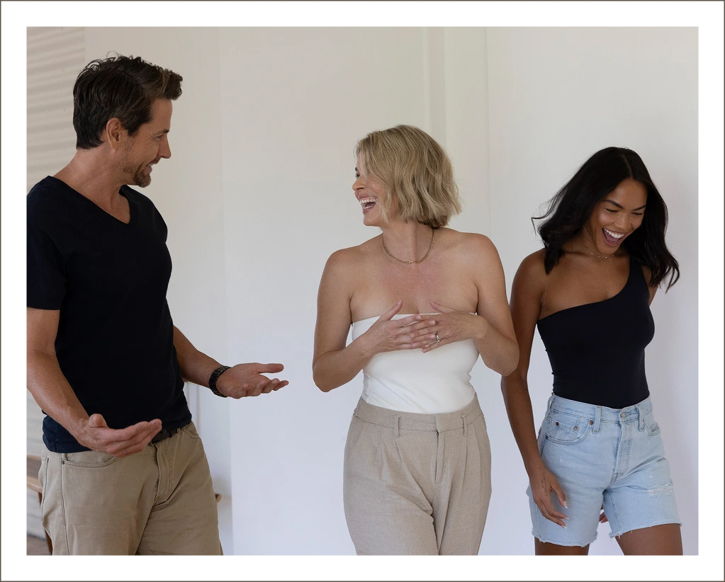 Three people smiling and conversing together in a bright room