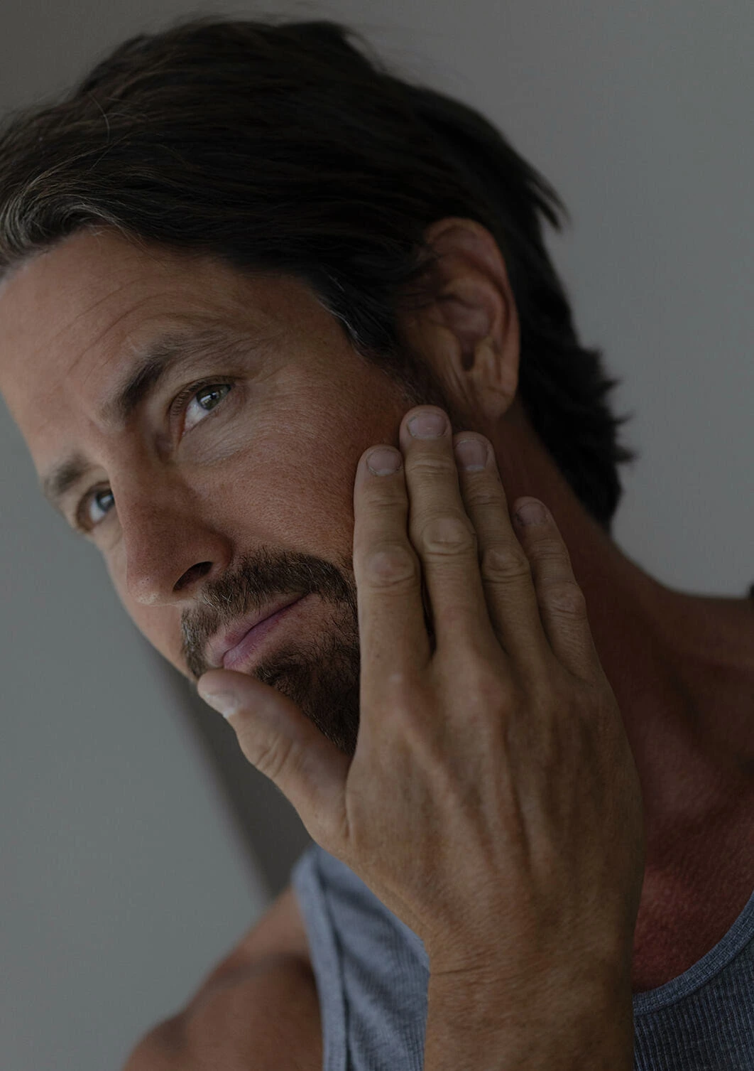 Man touching jaw and chin area, assessing skin laxity and facial contours