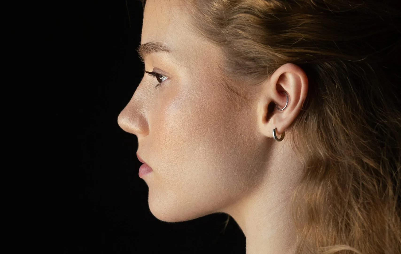 Woman in profile showing facial contours against black background