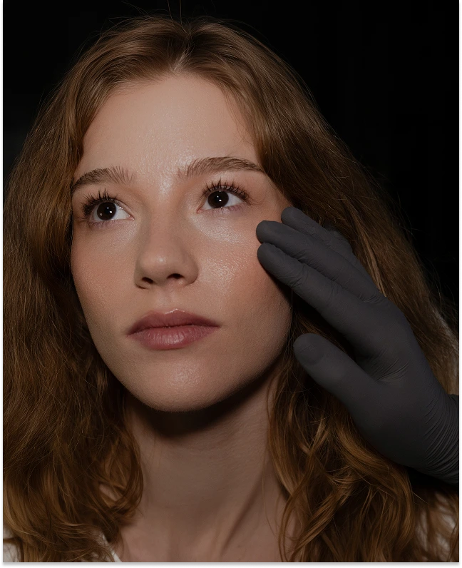 Practitioner in black gloves examining patient's cheekbone and skin texture