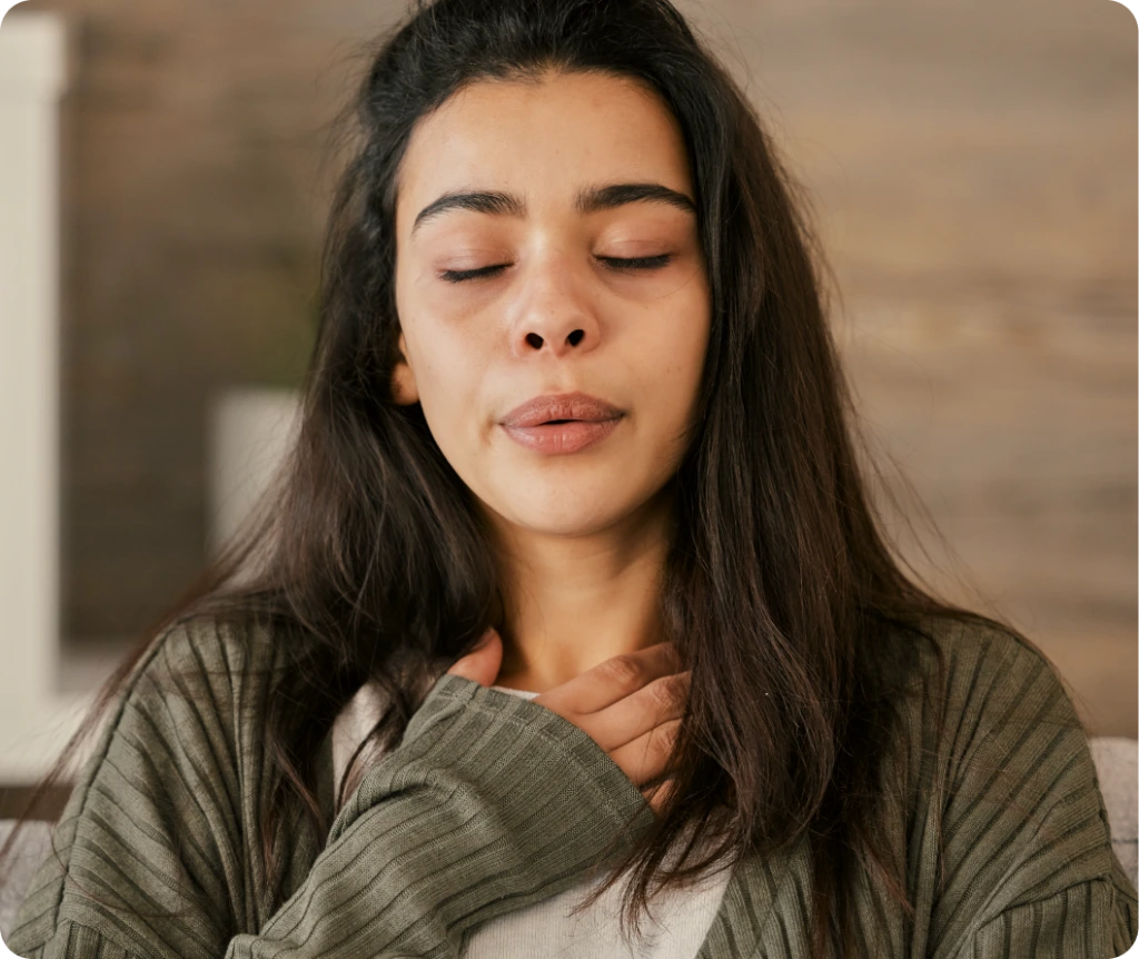 Woman with eyes closed, hand on chest, expressing emotional distress