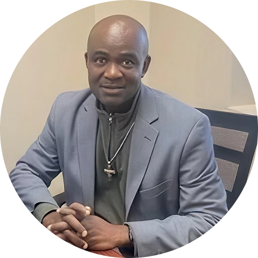 DR. UCHENNA ORJI, DNP, APRN, PMHNP-BC, FNP-BC, BA, seated at a desk wearing a blue blazer