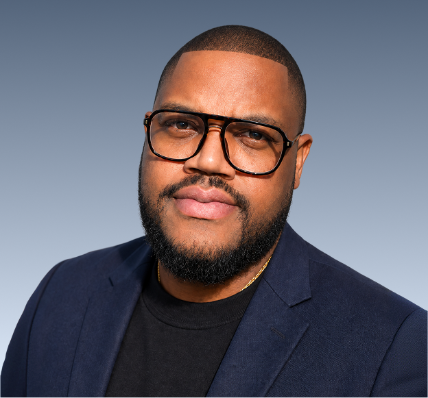 Professional headshot of a team member wearing glasses and navy blazer against blue background