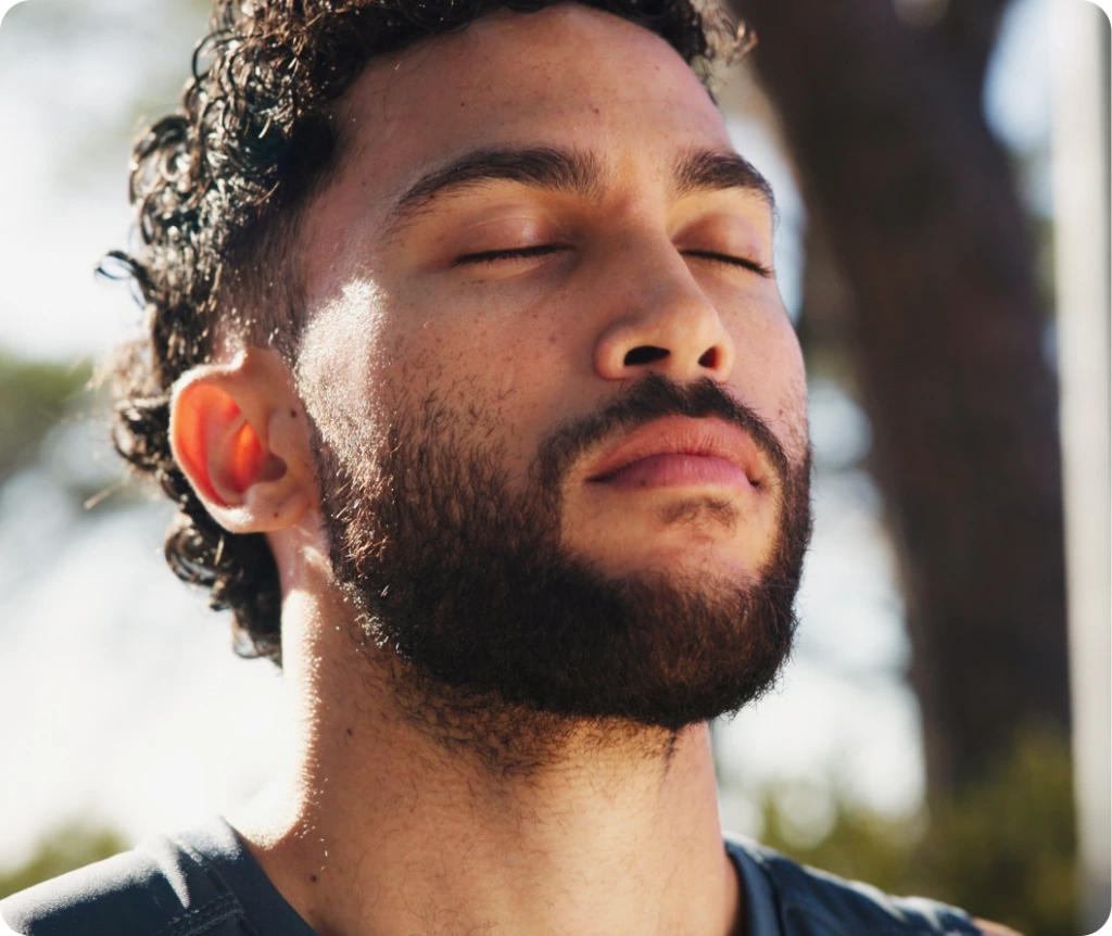 Man with eyes closed in a calm, meditative state outdoors