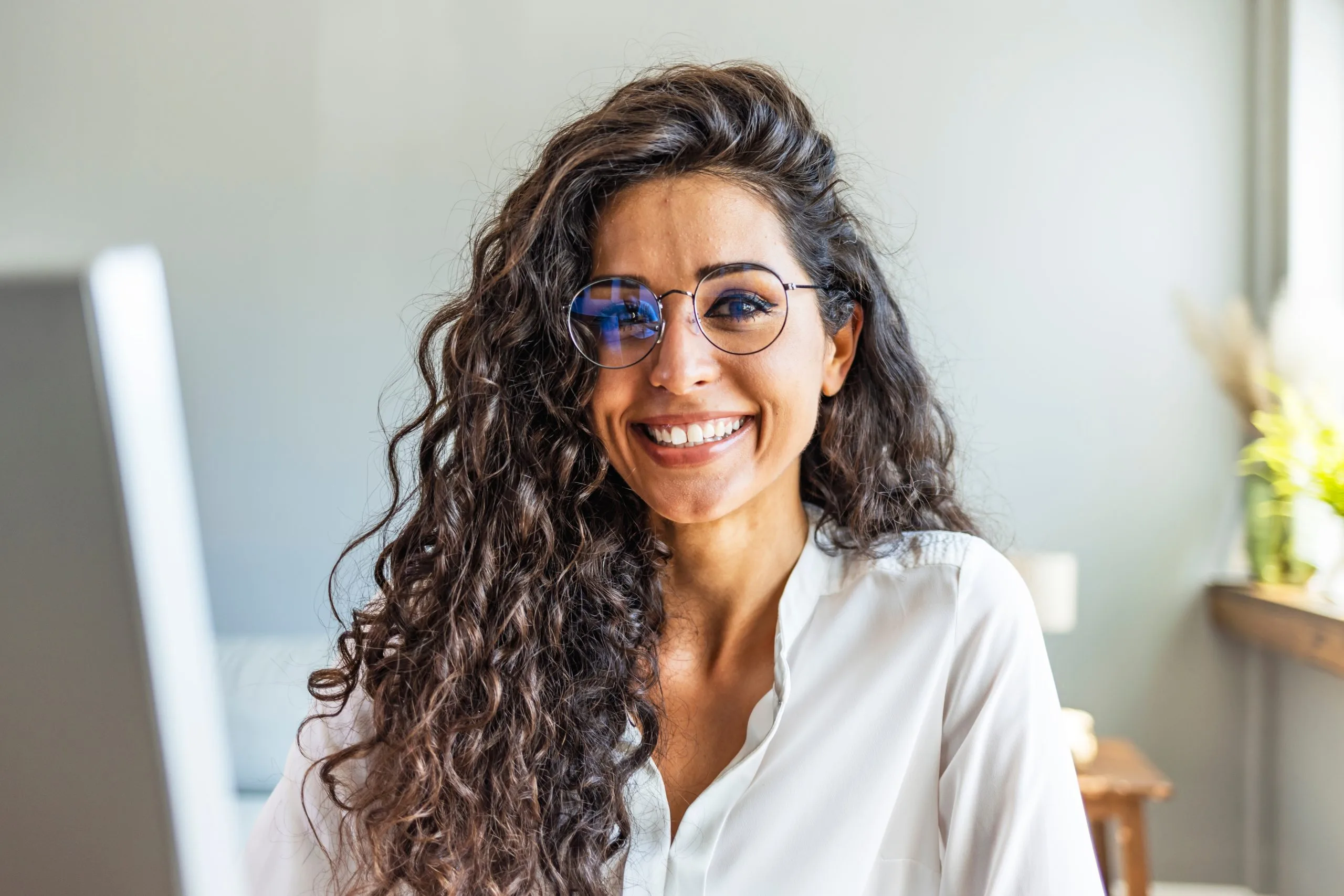 Professional woman smiling in a modern office setting with a laptop nearby