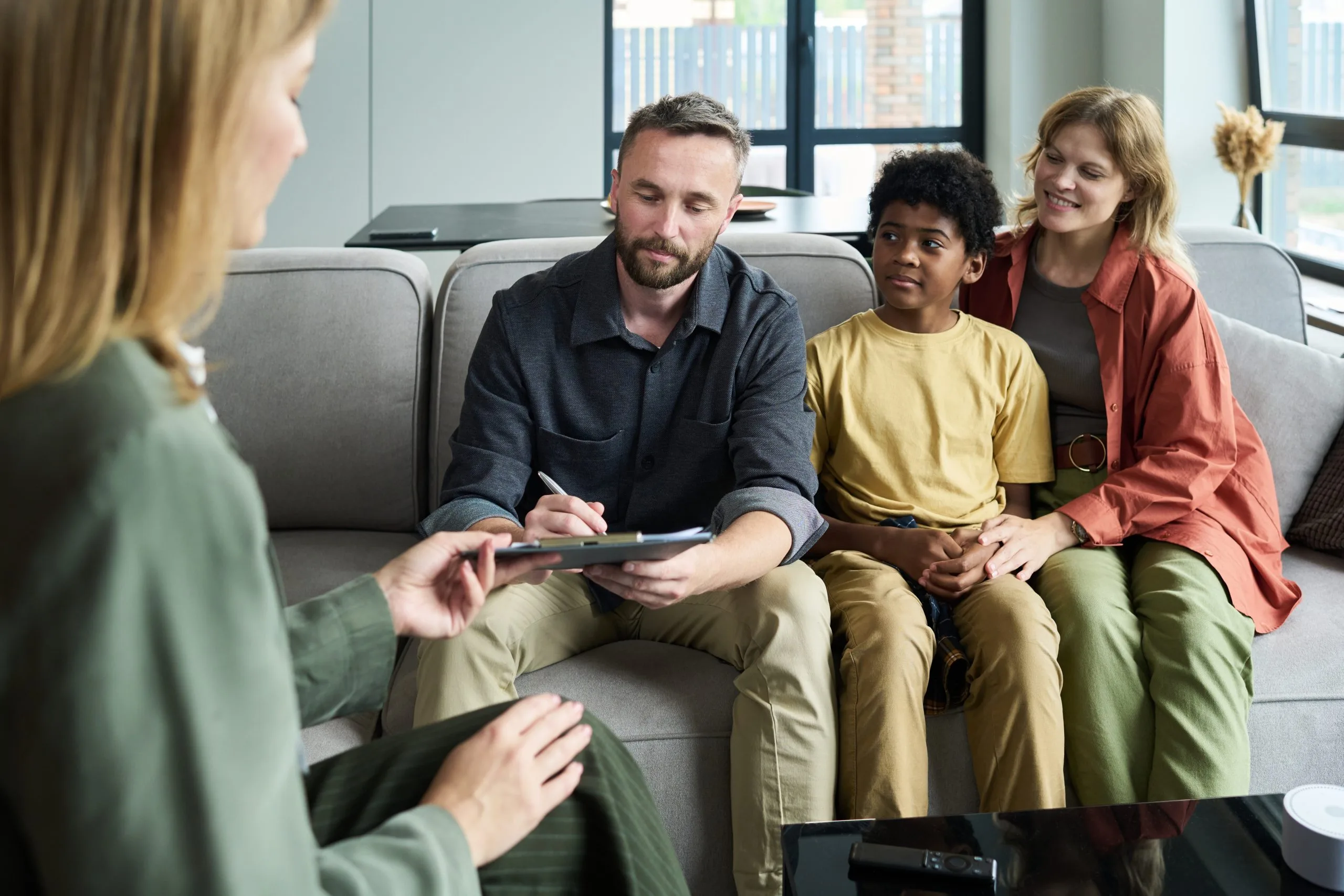 Family sitting together on a sofa during a family therapy session with a therapist
