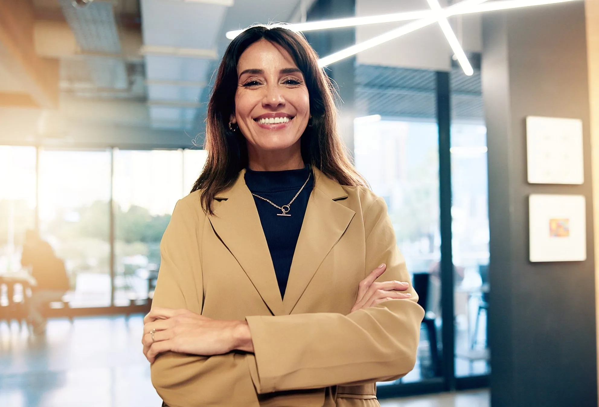 Professional woman smiling with arms crossed in a modern office setting