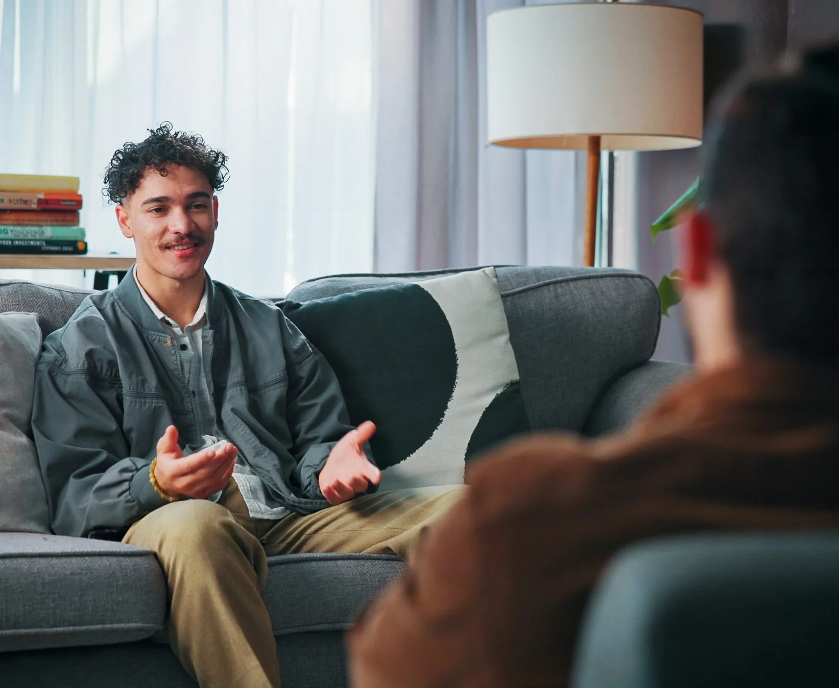 Man speaking with a therapist during a consultation in a bright office with bookshelves and plants
