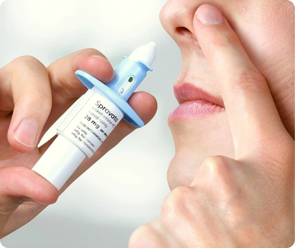 Patient holding Spravato nasal spray device near their nose