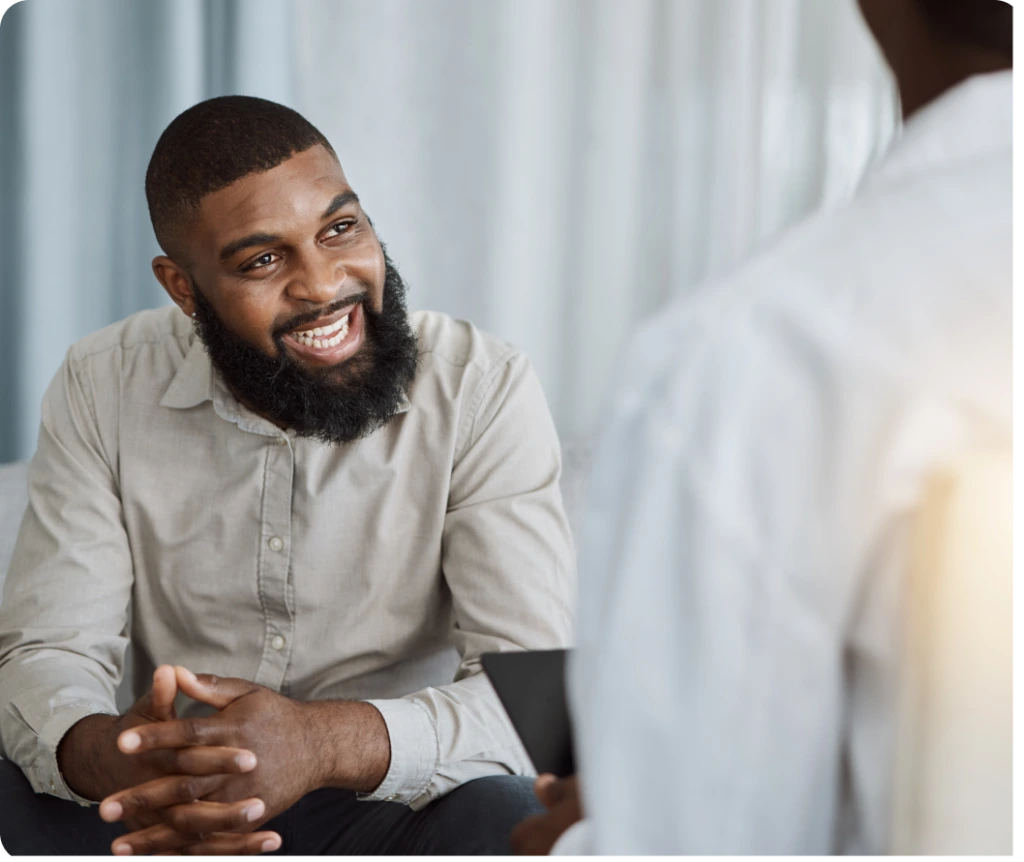 Man in beige shirt smiling during a therapy session with a provider
