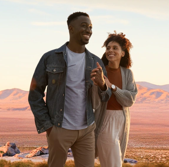 Couple walking together in a desert landscape at sunset