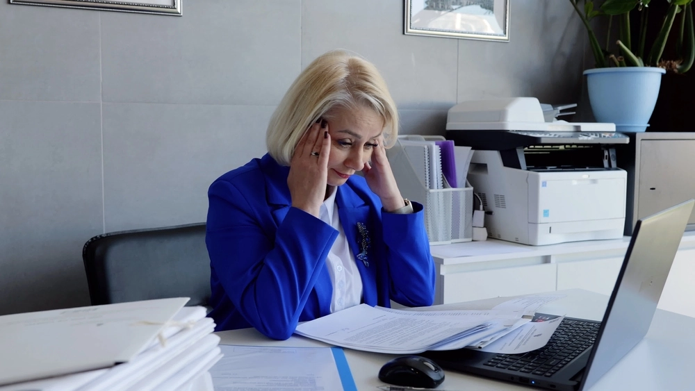 Business woman In Office Holding Head In Hands Overworking Emotional Stress
