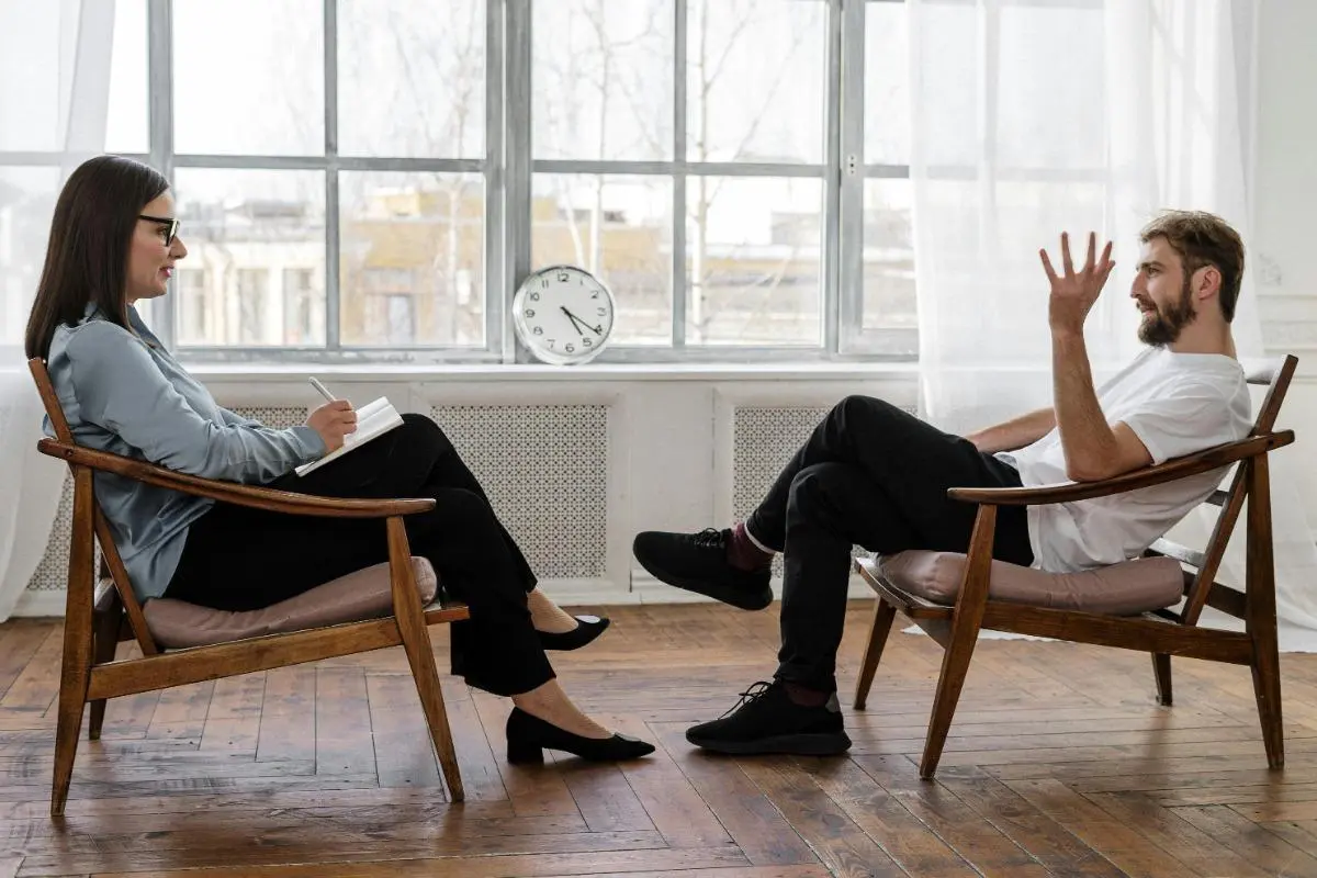Male client talking to female therapist in modern office therapy session