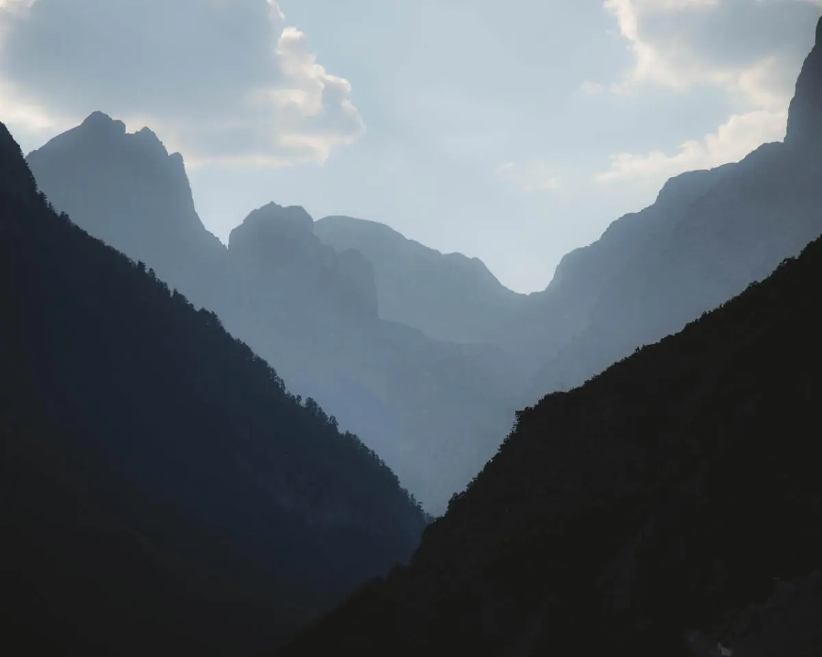 Silhouetted mountain range with layers of peaks under a cloudy sky
