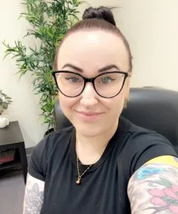 Jessica Sims, LICSW, seated in her office with a plant behind her