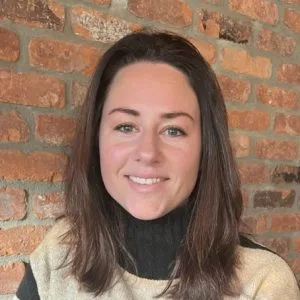 Meg Asselin, LMHC, smiling at camera against a brick wall