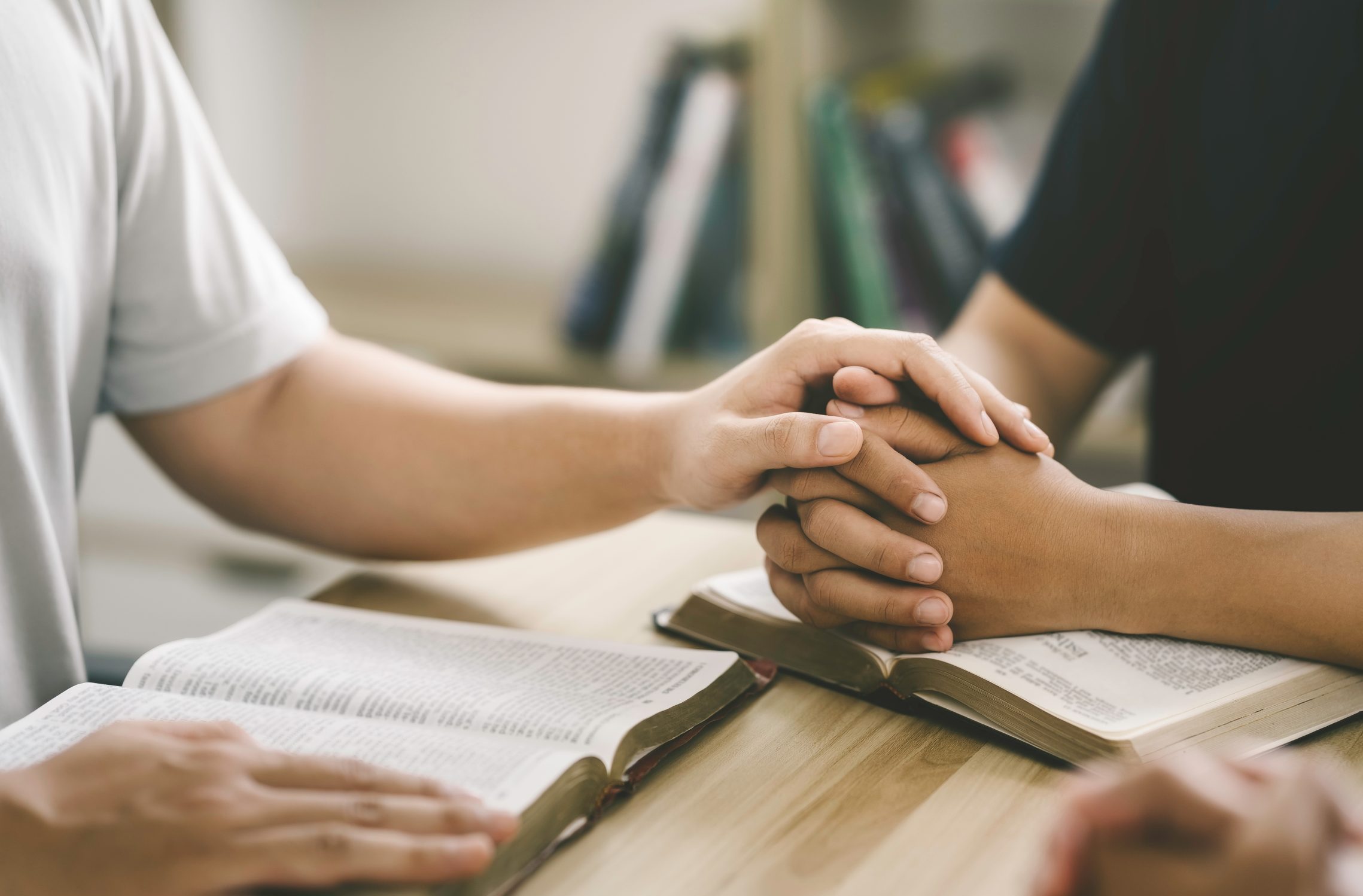 Clasped hands resting on an open Bible