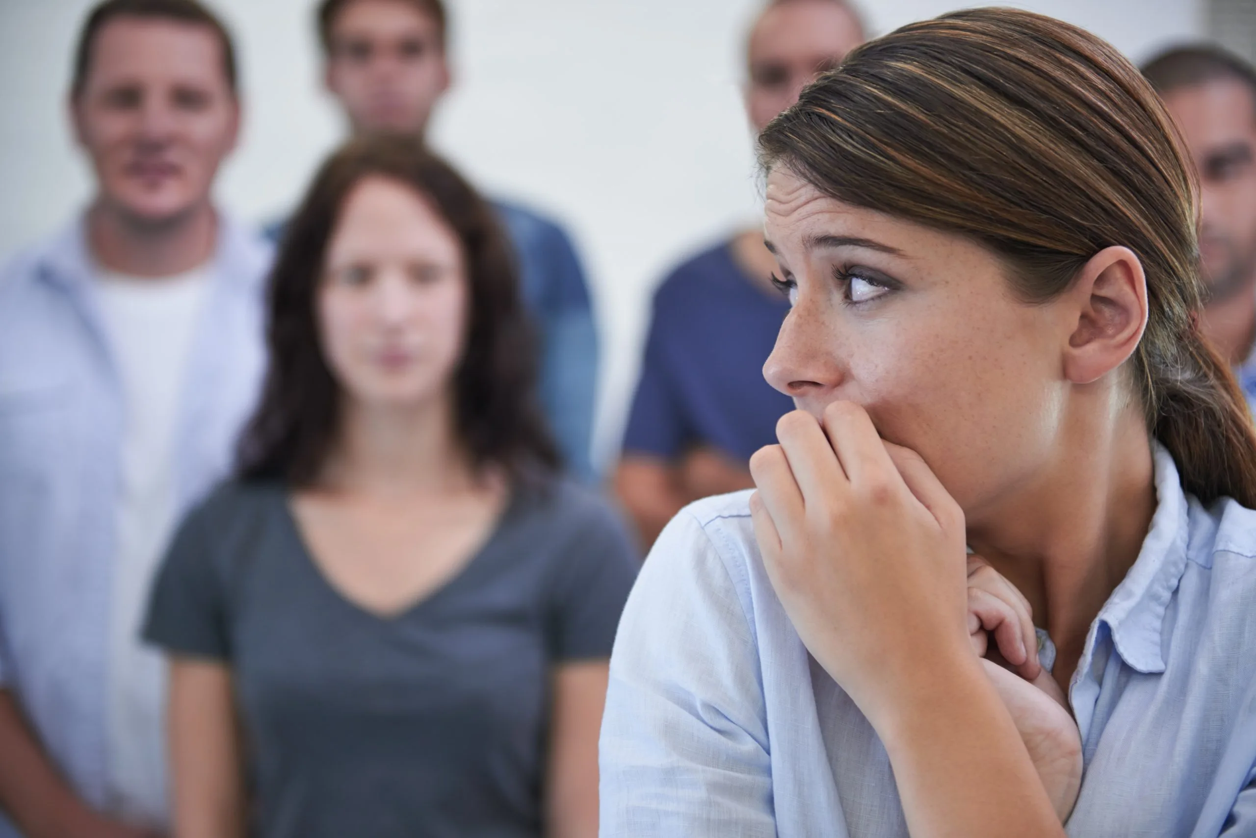 Anxious young woman in front of a group