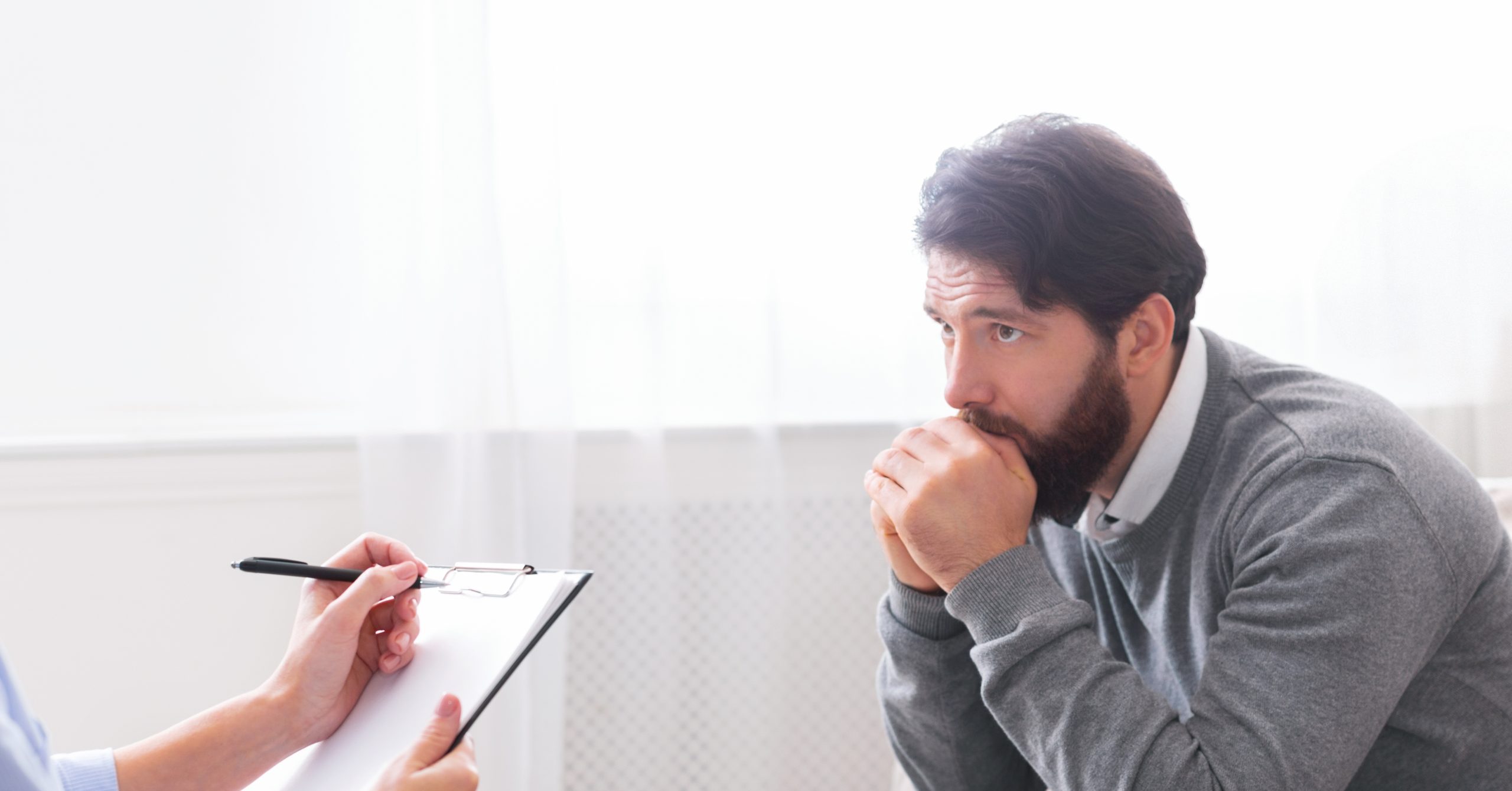 Man talking with a therapist who takes notes