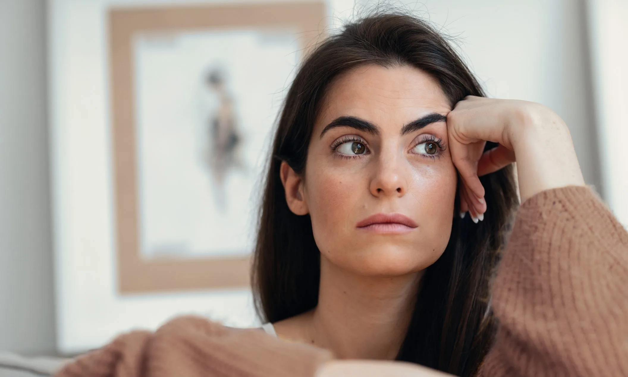 Exhausted woman holding her head on a couch