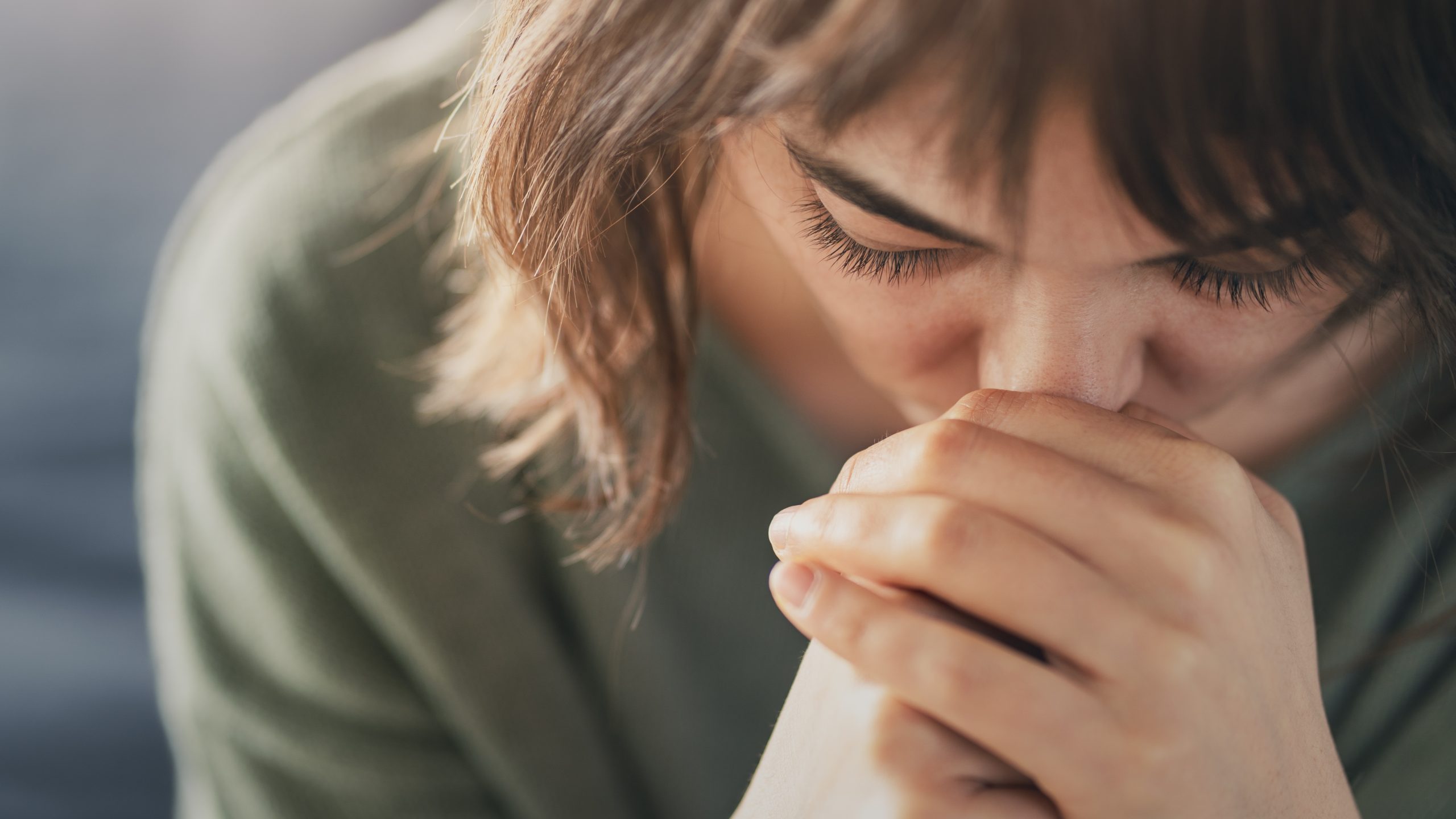 Woman with clasped hands pressed to her face