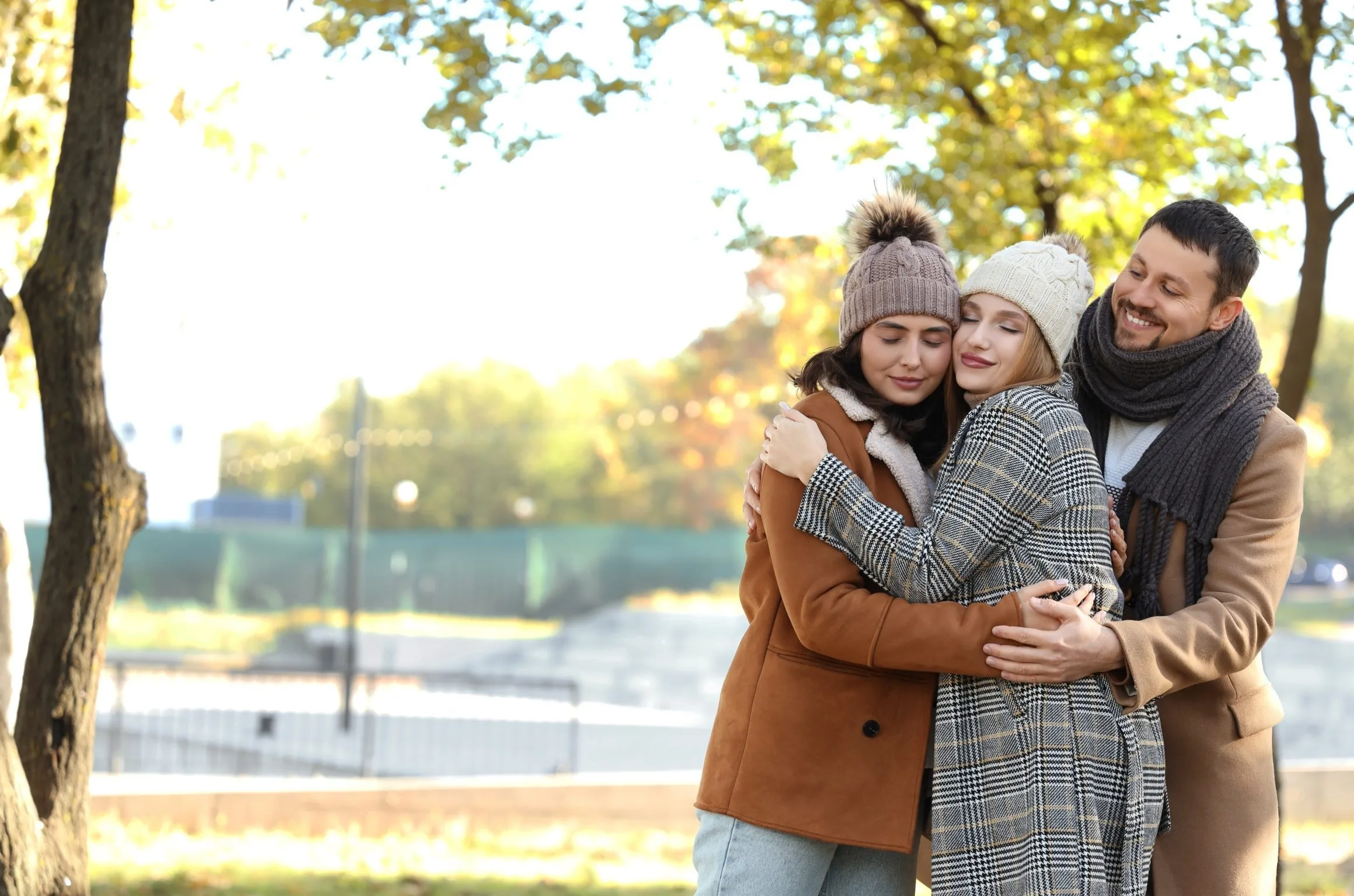 Three adults hugging in a park