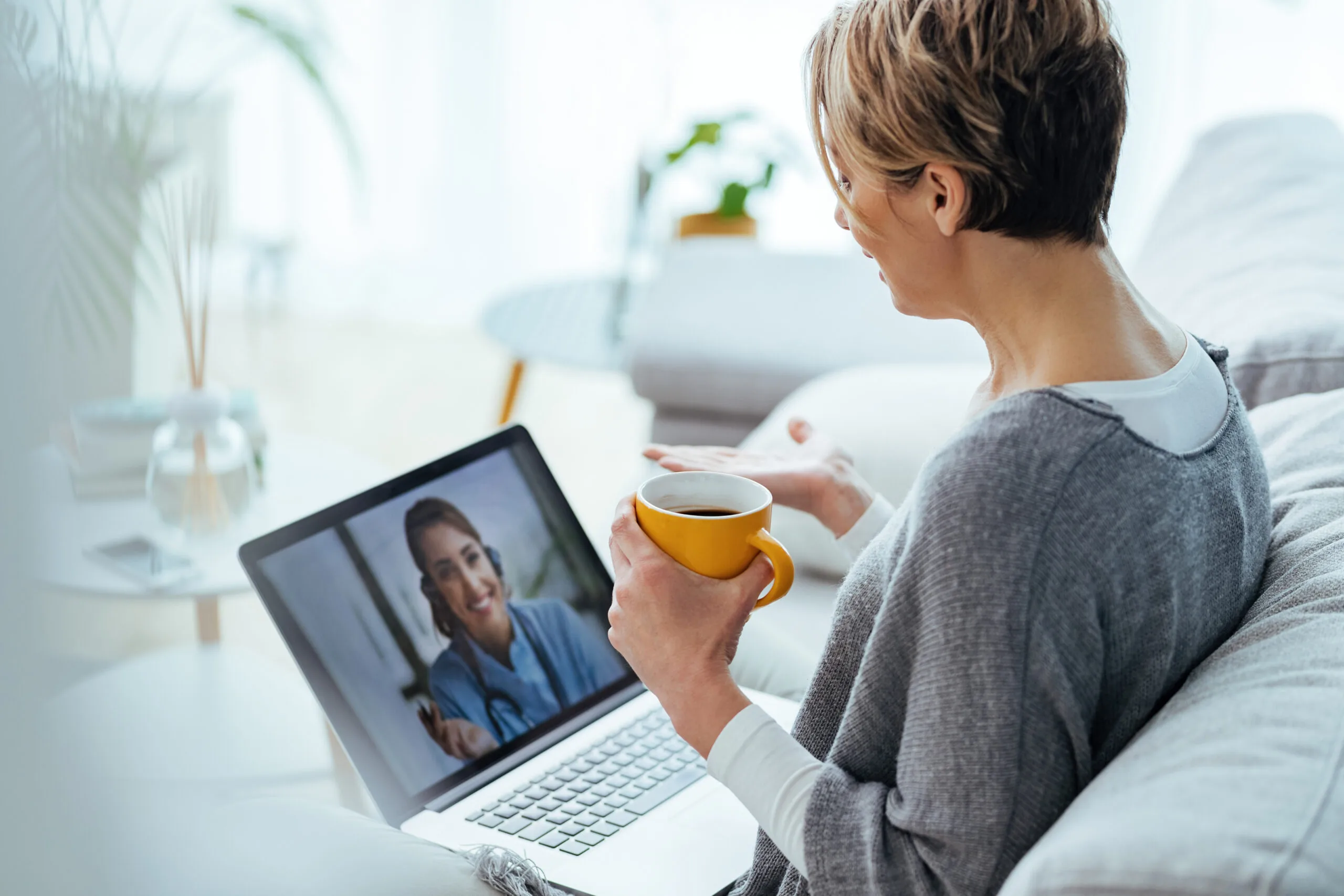 Woman sitting on the sofa while making video call over laptop with her doctor