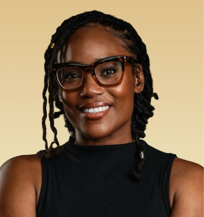 Acquisha Cagilus, therapist, smiling at the camera against a warm beige background