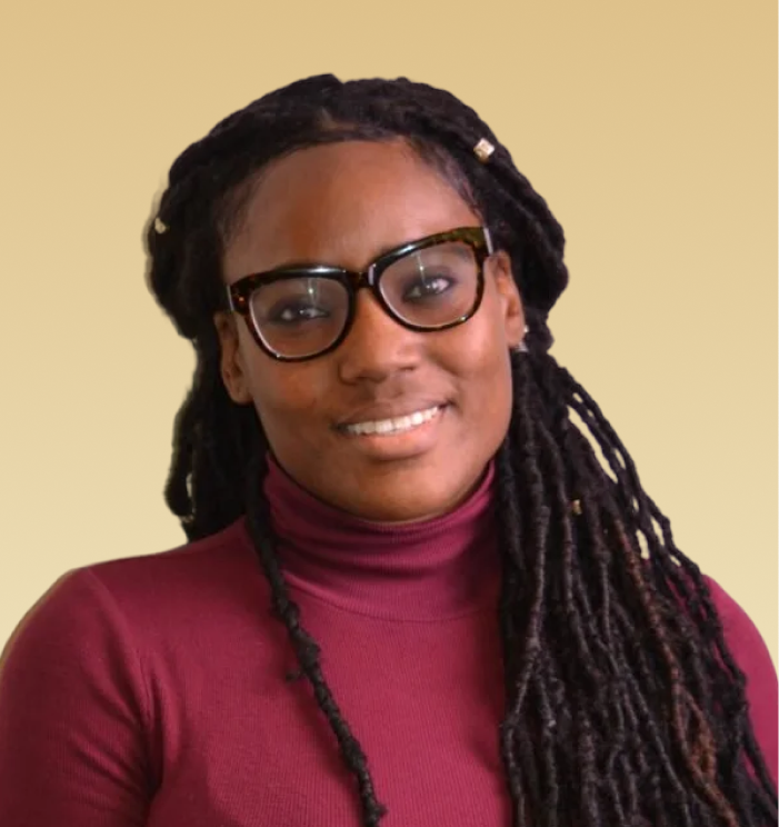 Acquisha Cagilus, MA, LPC, LCPC, smiling at camera wearing glasses and burgundy turtleneck
