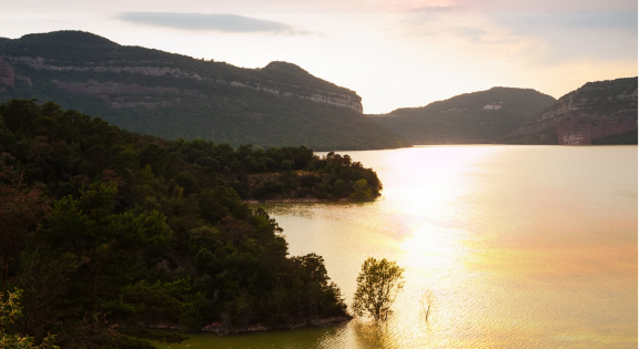 Scenic sunset over a calm lake surrounded by forested mountains