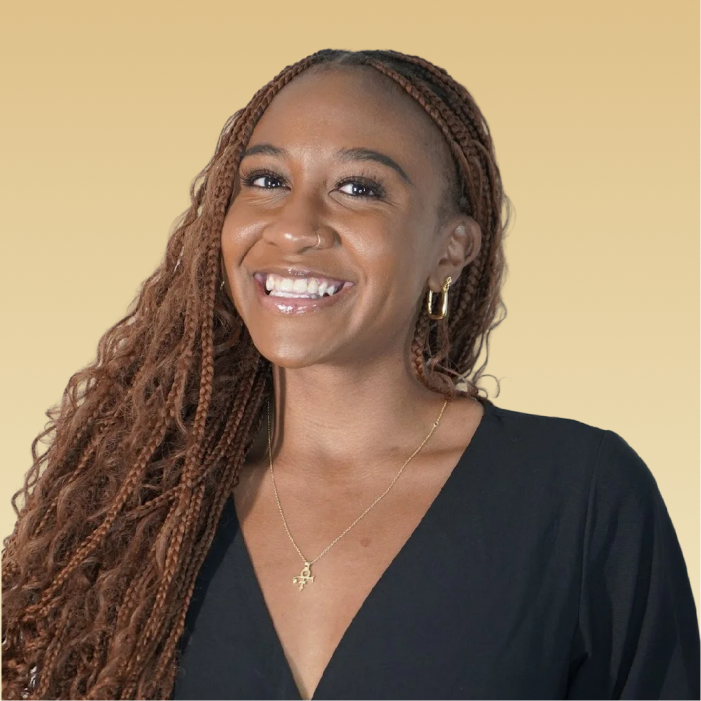 Team member smiling at camera against yellow background