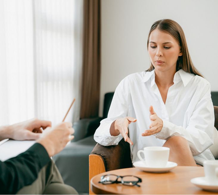 Therapist in white shirt gesturing while speaking with patient during narrative therapy session
