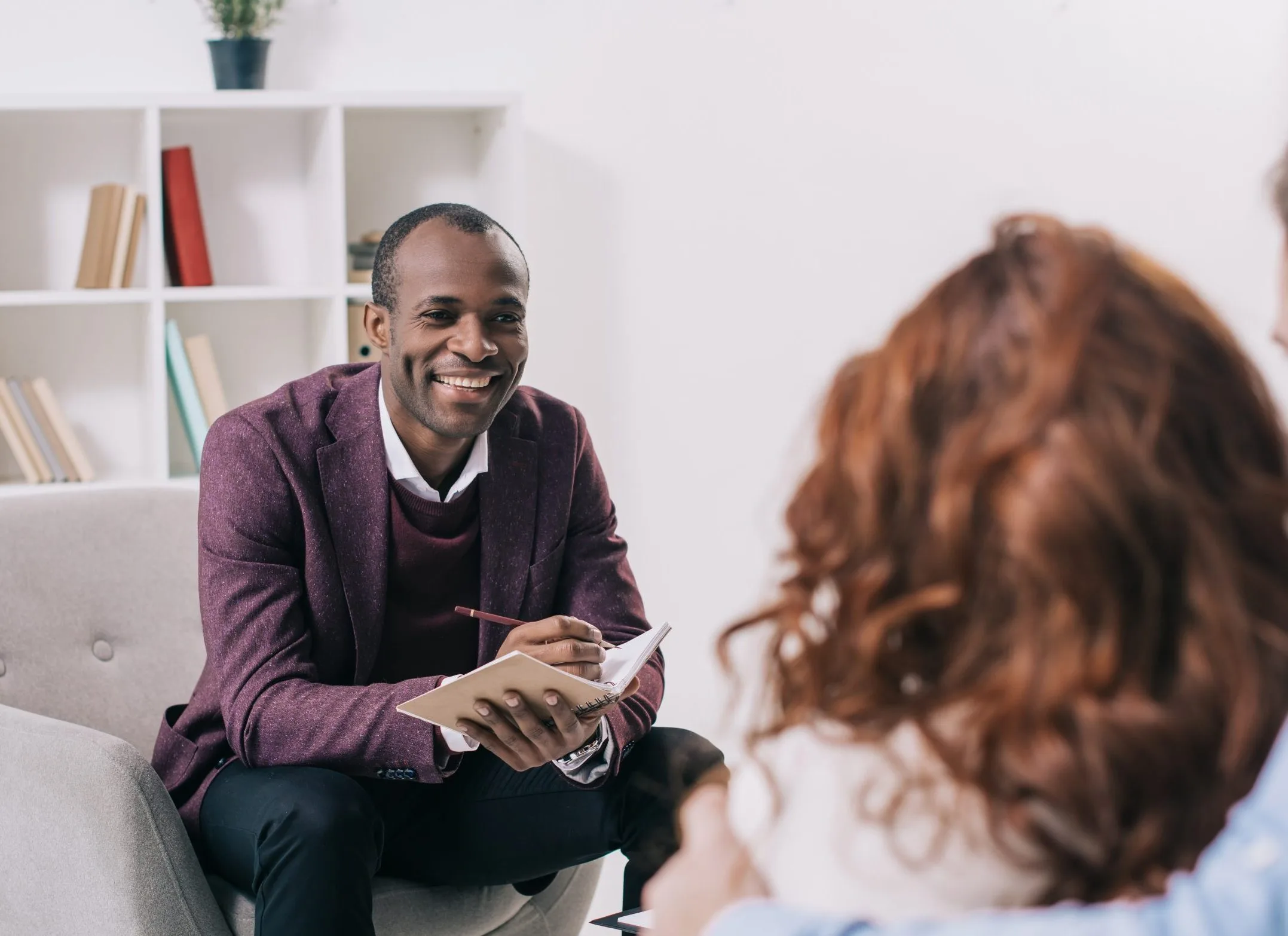 Therapist taking notes while listening to a patient during a consultation session