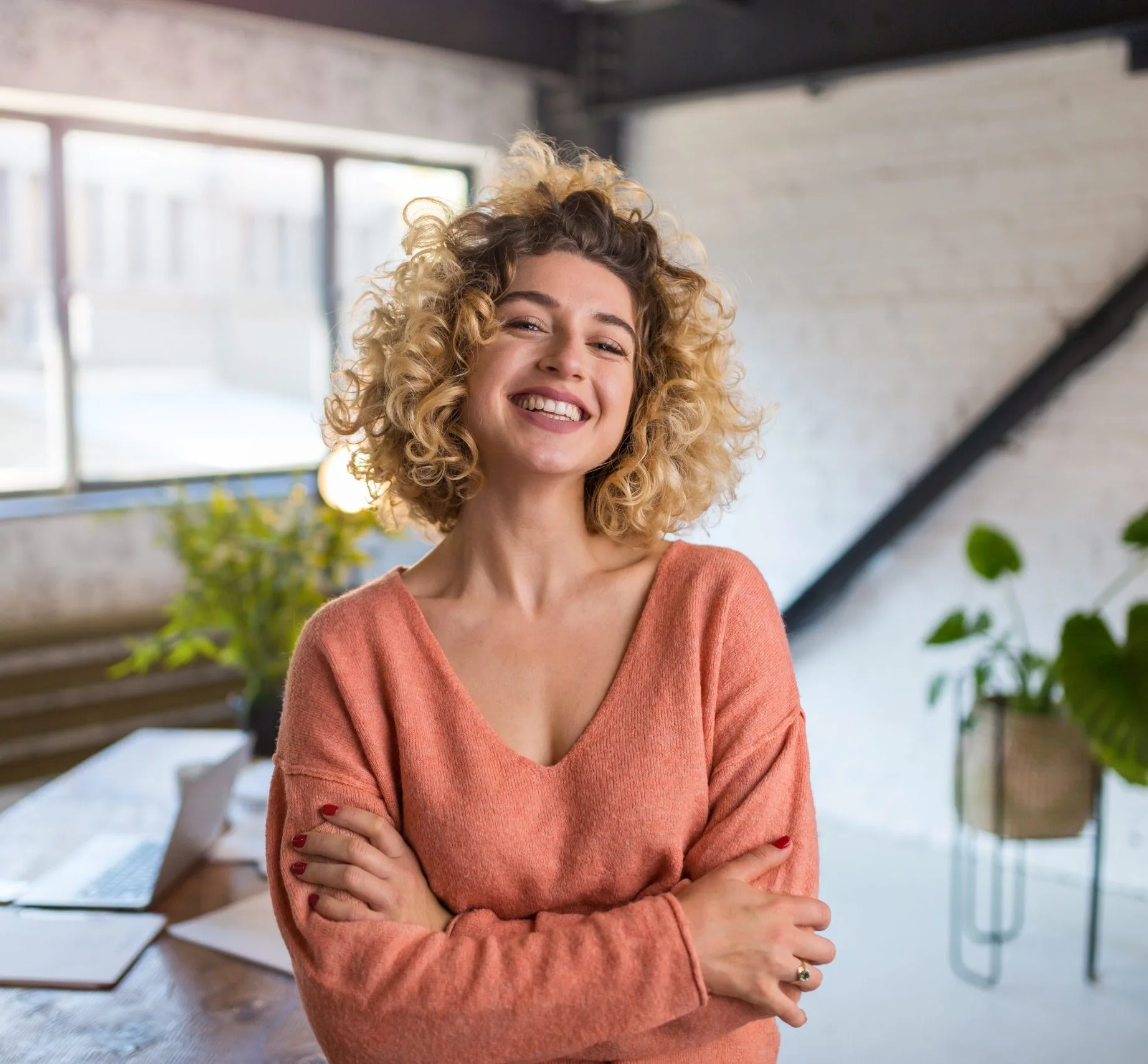 Confident woman smiling in a bright office with plants and windows
