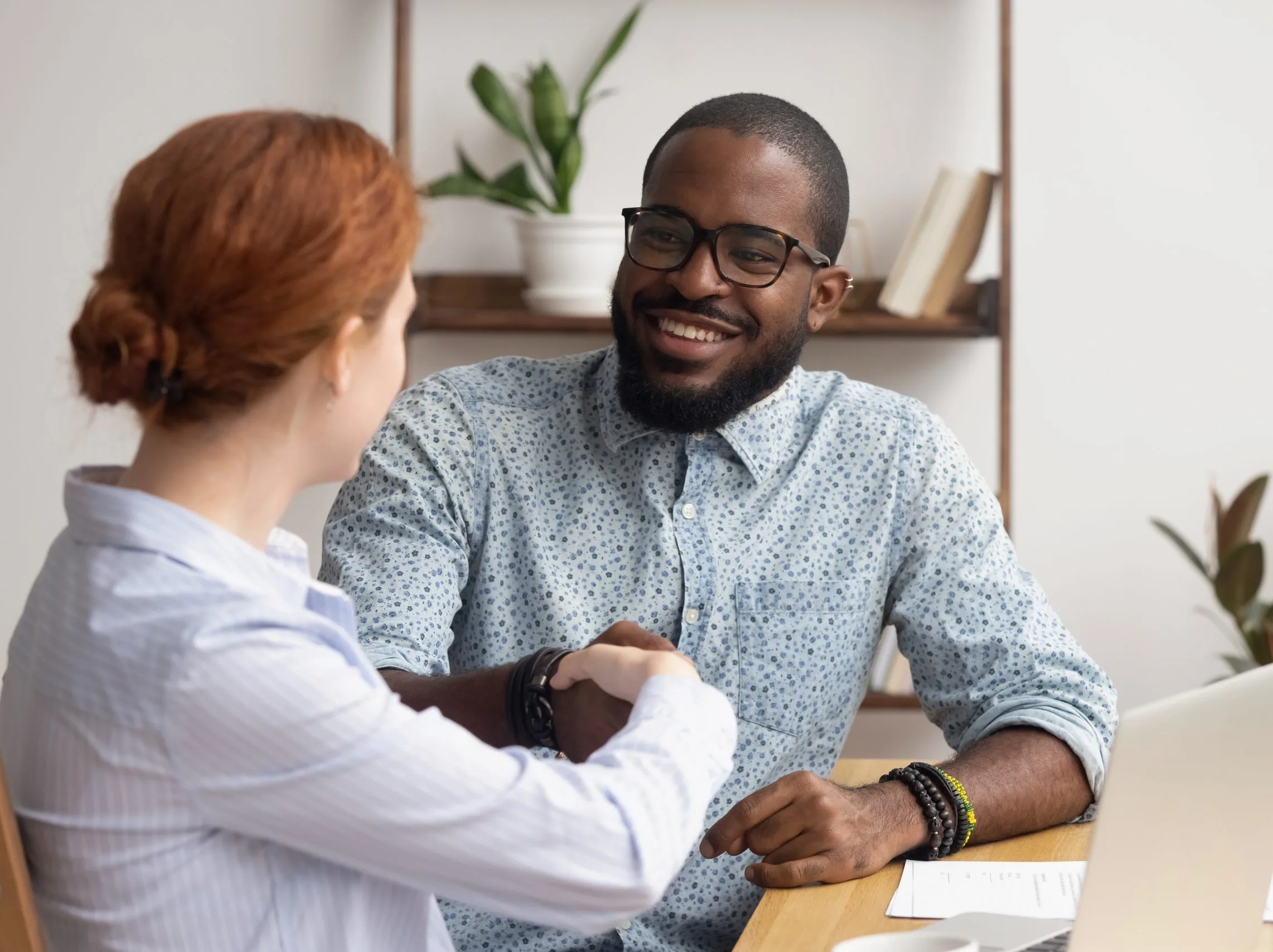 A therapist and patient shaking hands during a medication management consultation in a calm office setting