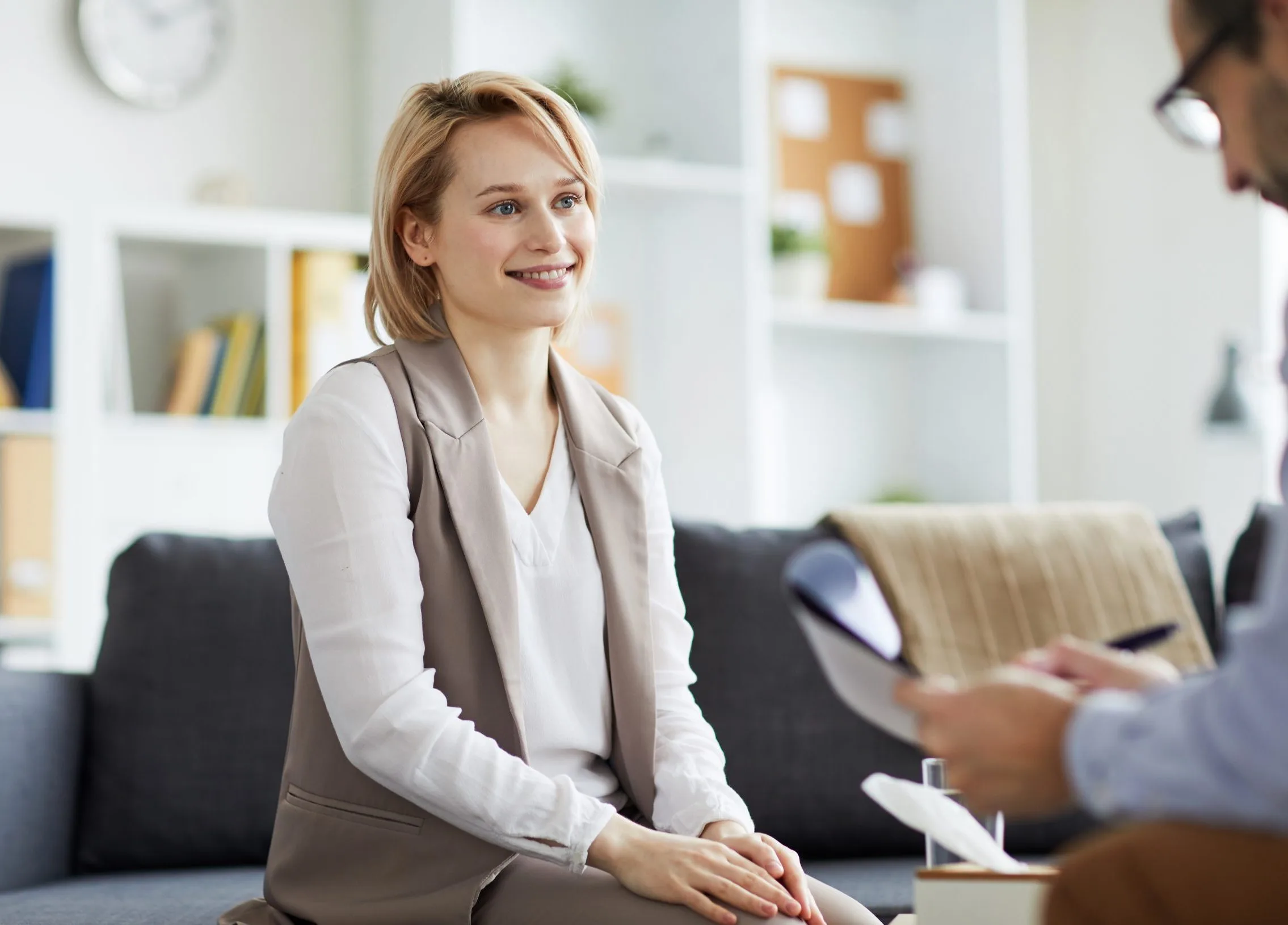 Woman sitting on a couch speaking with a healthcare provider during a consultation