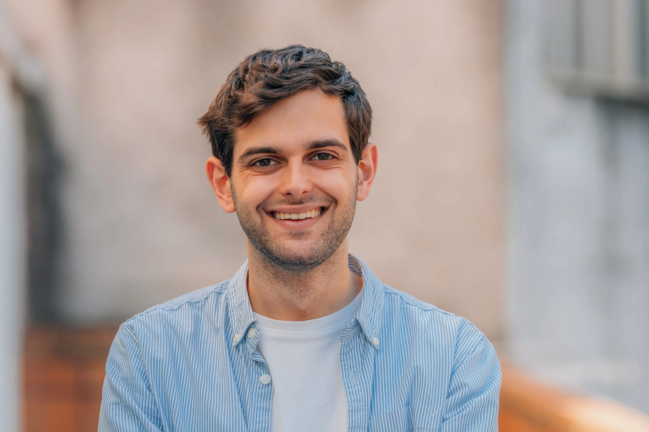 Young man smiling outdoors in a blue striped shirt