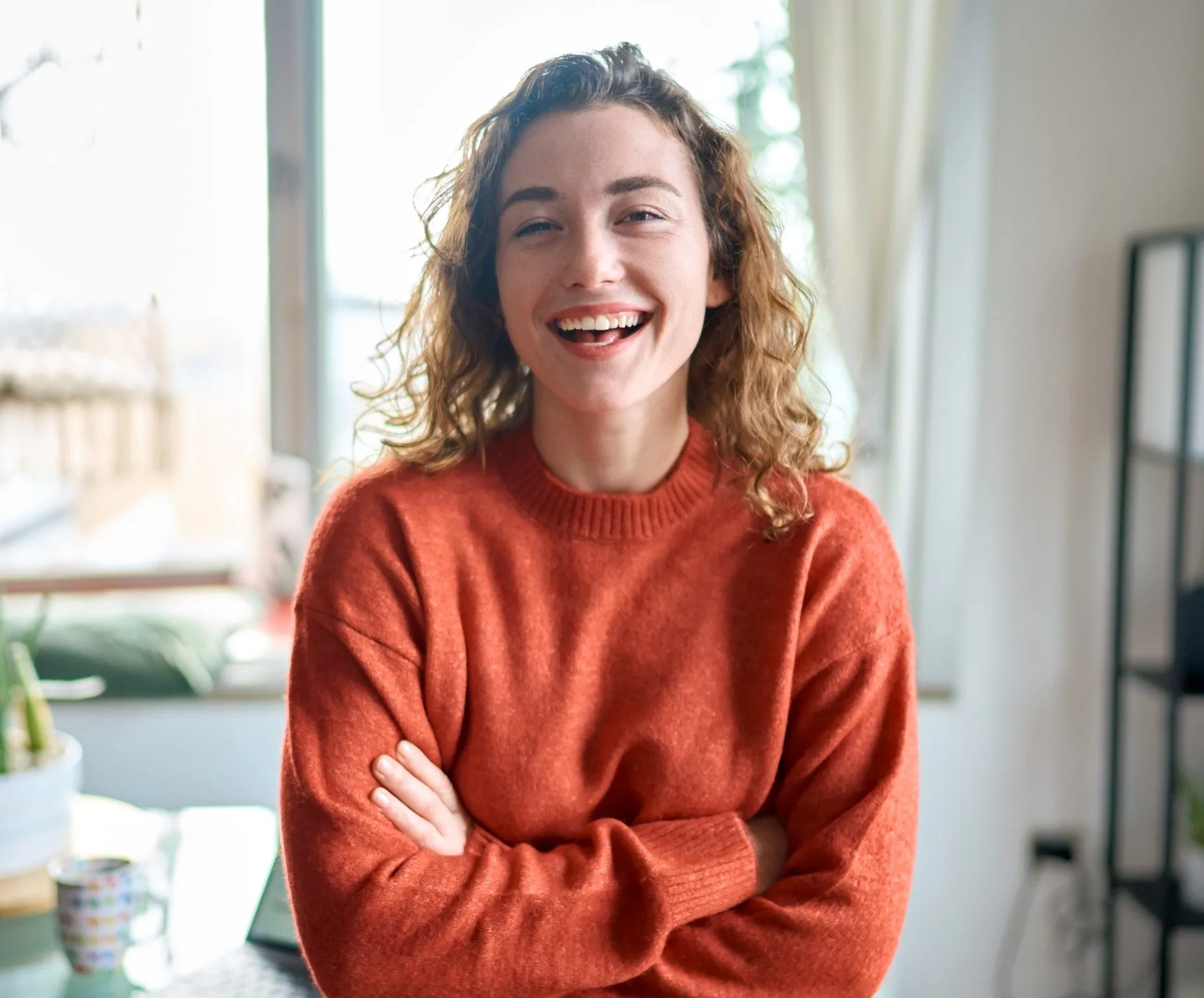 Woman in red sweater smiling at camera in bright office setting
